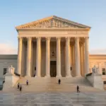 A grand, neoclassical US government building exterior at dawn, bathed in warm golden hour sunlight